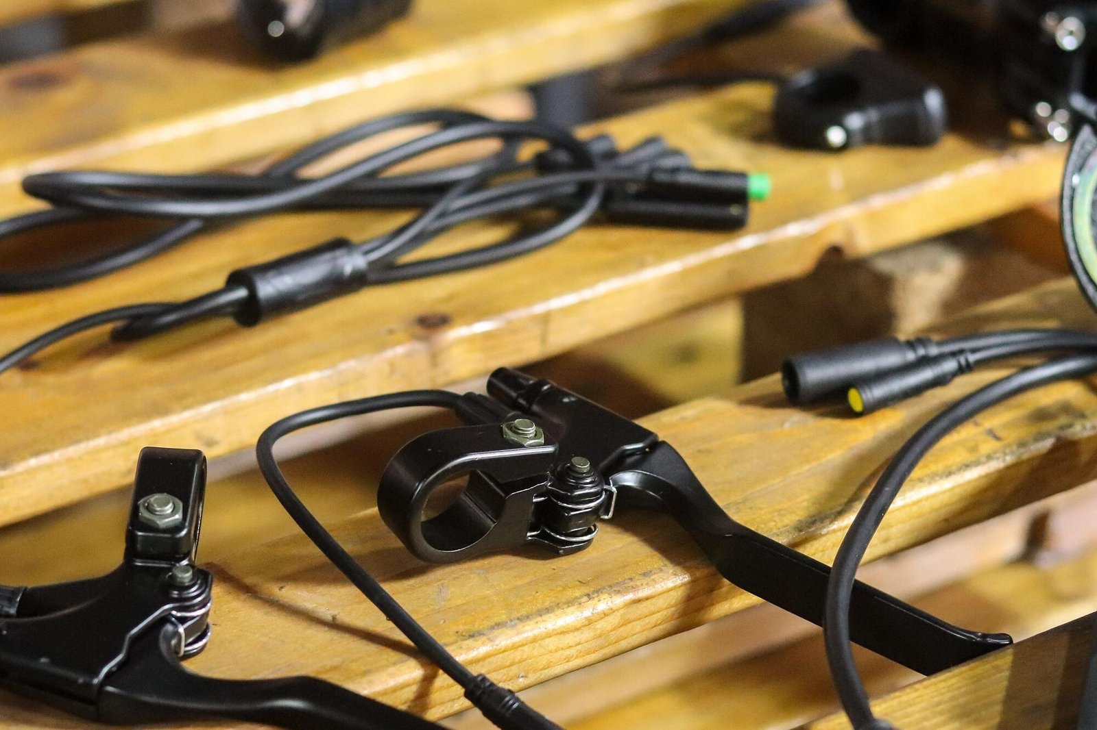 Componentes e cabos de bicicleta elétrica organizados sobre uma bancada de trabalho.